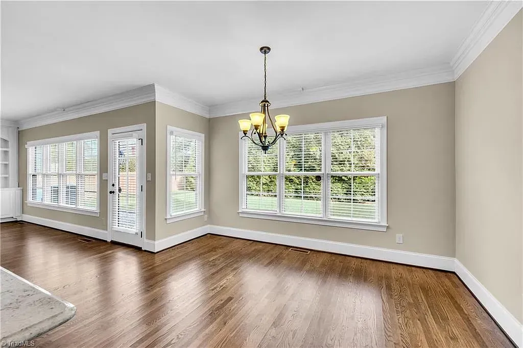An empty living room with hardwood floors and a chandelier.