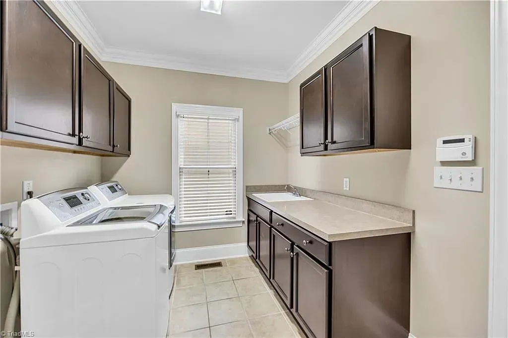 A laundry room with a washer and dryer and cabinets.
