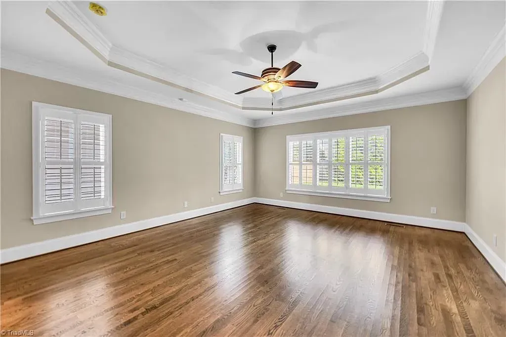 An empty living room with hardwood floors and a ceiling fan.