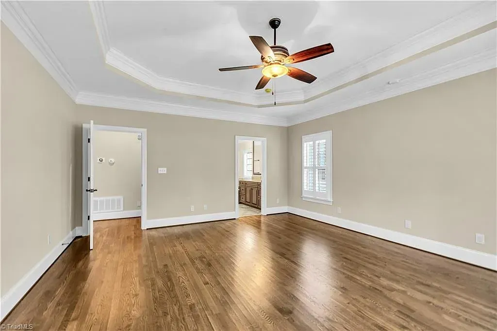 A large empty room with hardwood floors and a ceiling fan.