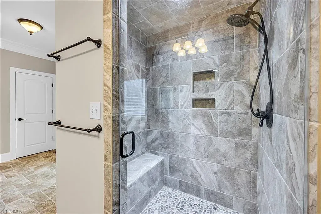 A bathroom with a walk in shower and a towel rack.