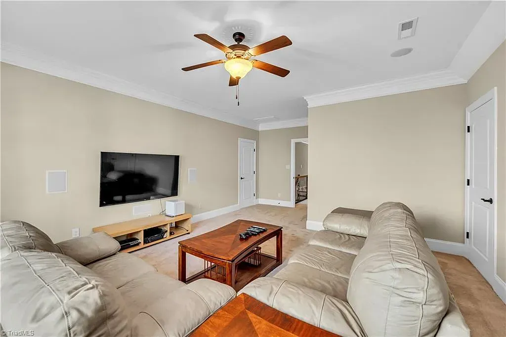 A living room with a ceiling fan and a flat screen tv.