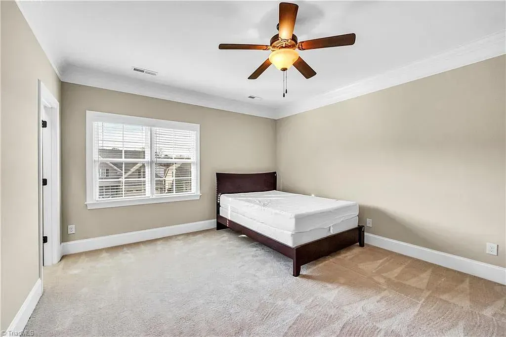 A bedroom with a bed and a ceiling fan.