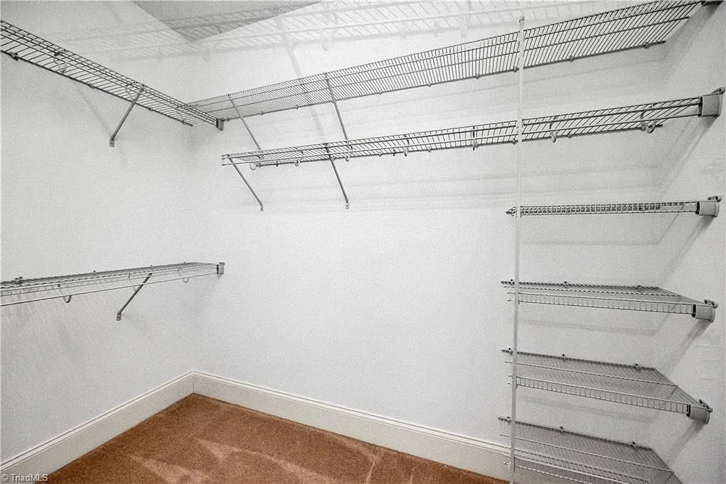 An empty walk in closet with lots of shelves