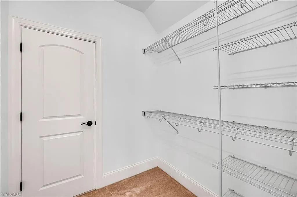 A walk in closet with lots of shelves and a door.