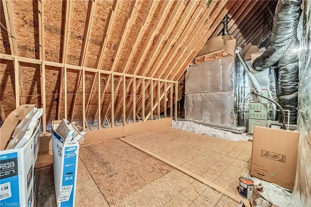 An attic under construction with wooden beams and boxes on the floor.