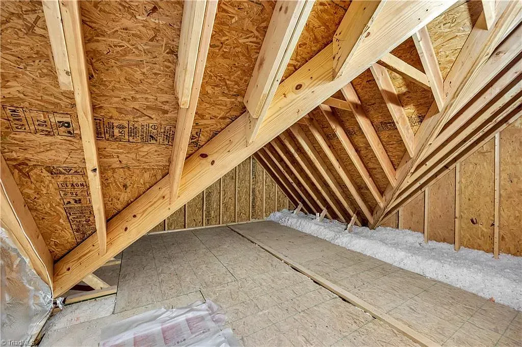 An attic under construction with wooden beams and insulation.