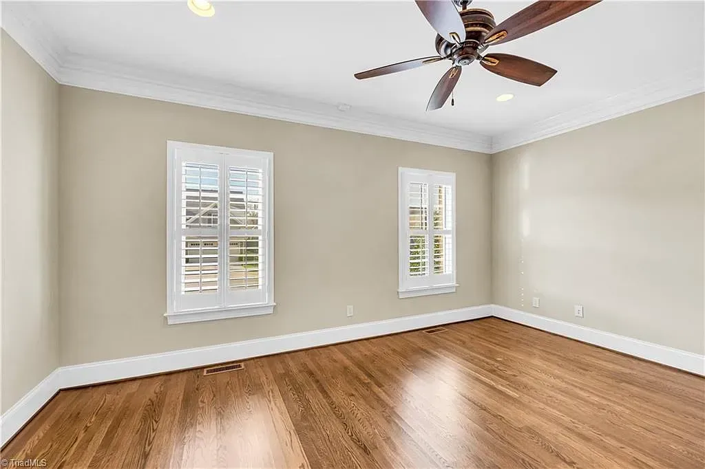 An empty room with hardwood floors and a ceiling fan.