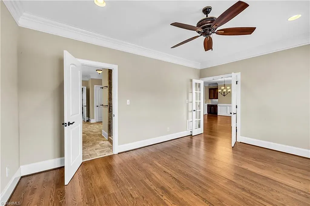 An empty living room with hardwood floors and a ceiling fan.