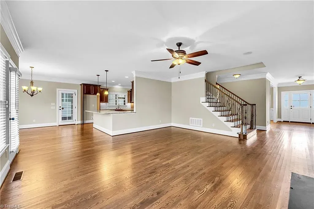 A large empty living room with hardwood floors and a ceiling fan.