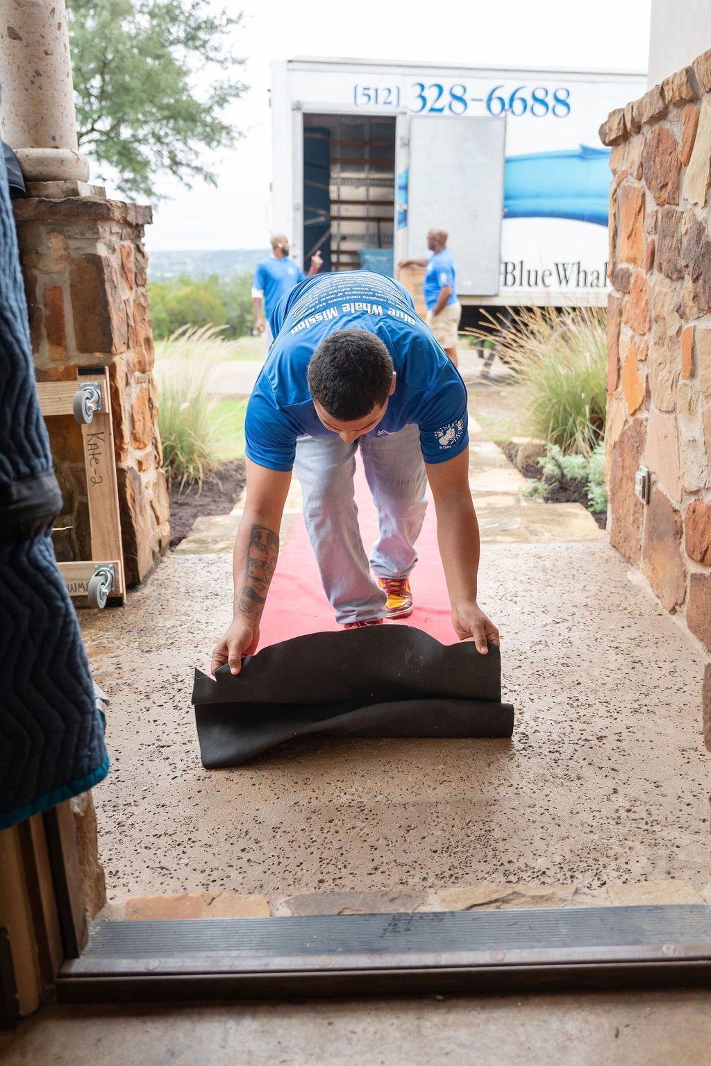 A man is laying a red carpet in front of a moving truck.