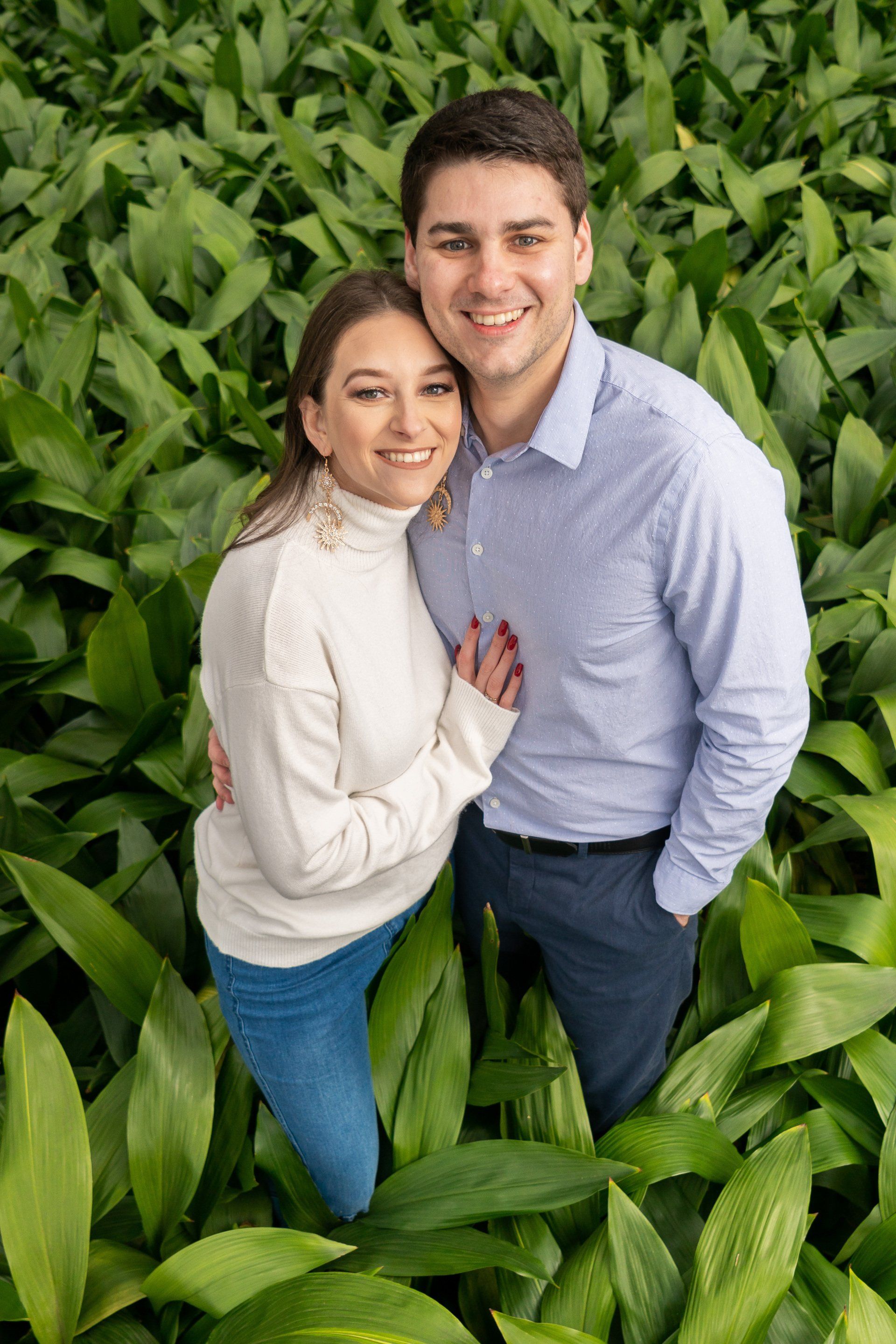 A man and a woman are posing for a picture in a field of plants.