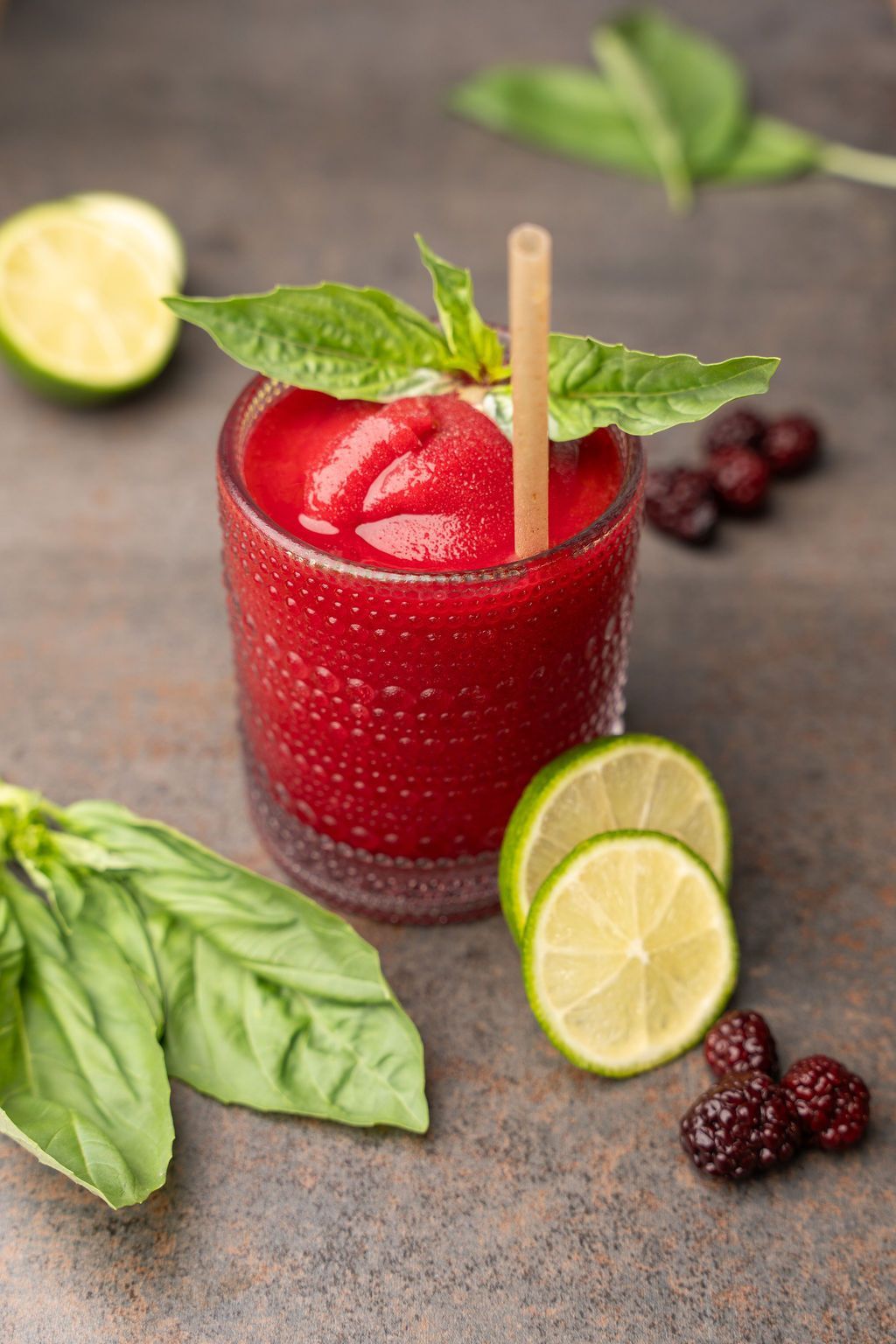 A close up of a red drink in a glass with a straw.