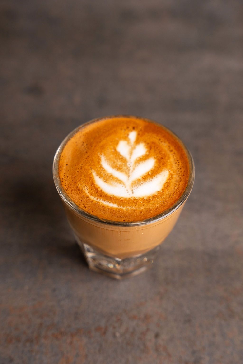 A close up of a cup of cappuccino with latte art on a table.