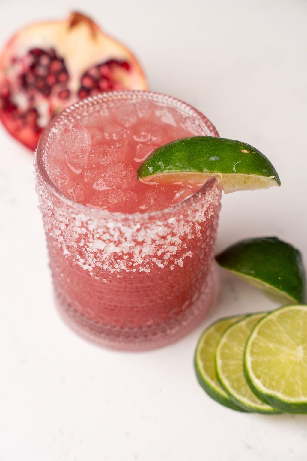 A close up of a margarita with a slice of lime on a table.