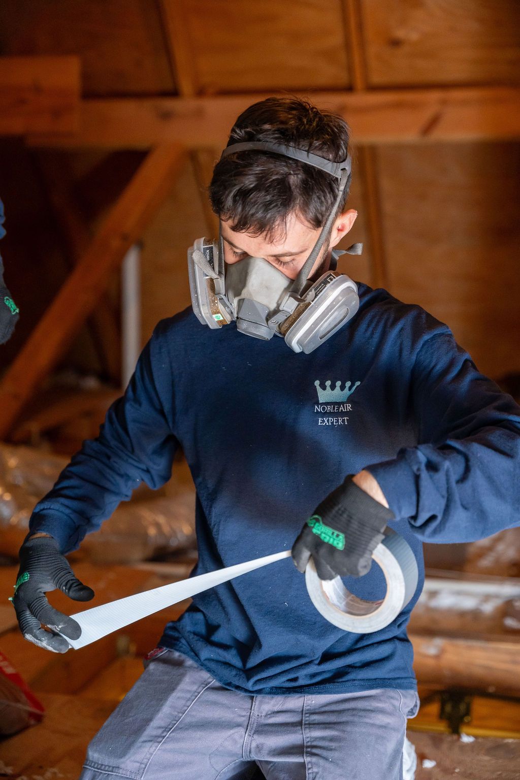 A man wearing a gas mask is cutting a roll of tape.