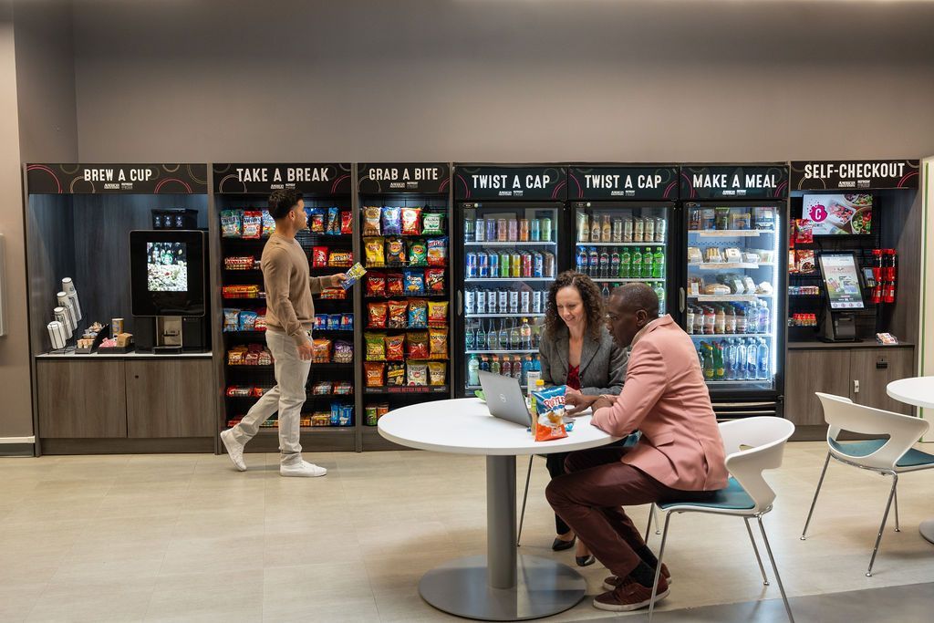 A group of people are sitting at a table in front of a vending machine.