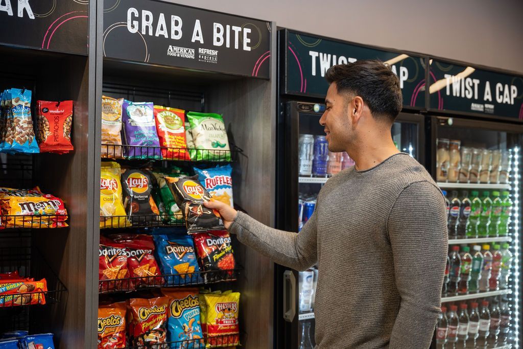 A man is standing in front of a vending machine.