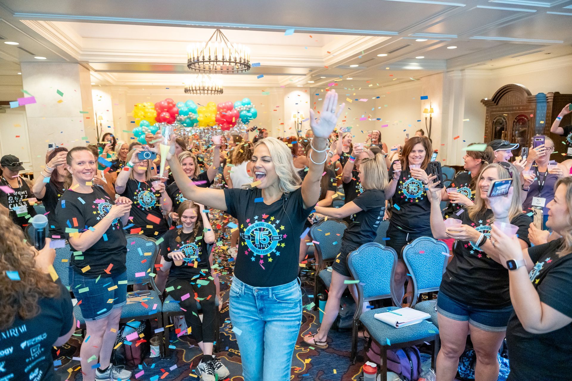 A group of people are standing in a room with confetti and balloons.