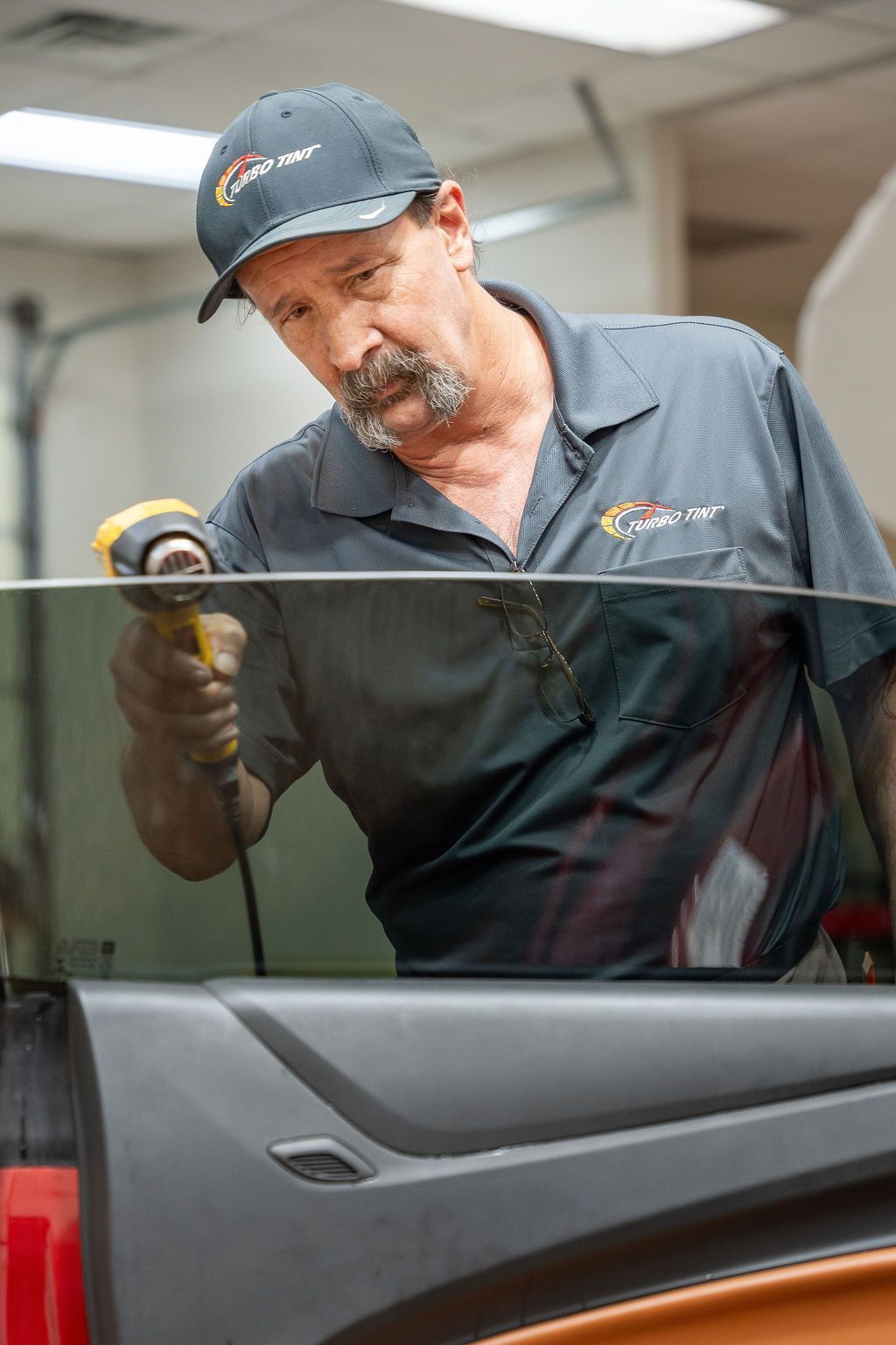 A man is working on a car window with a tool.