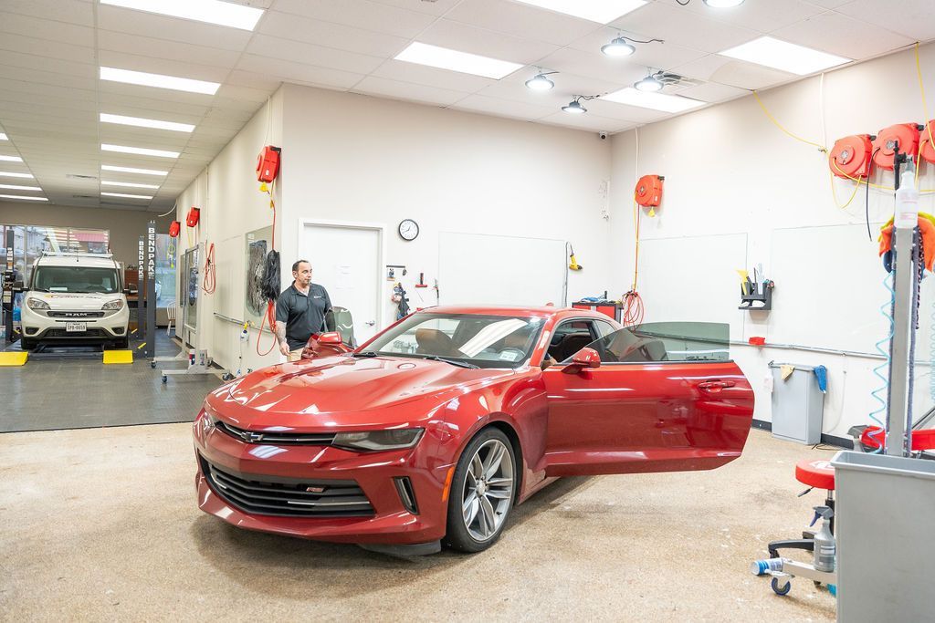 A red car is parked in a garage with its doors open.