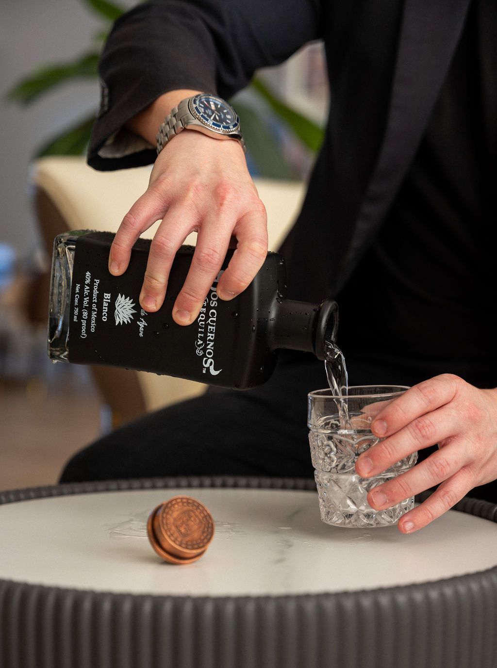 A man is pouring a drink from a bottle into a glass.