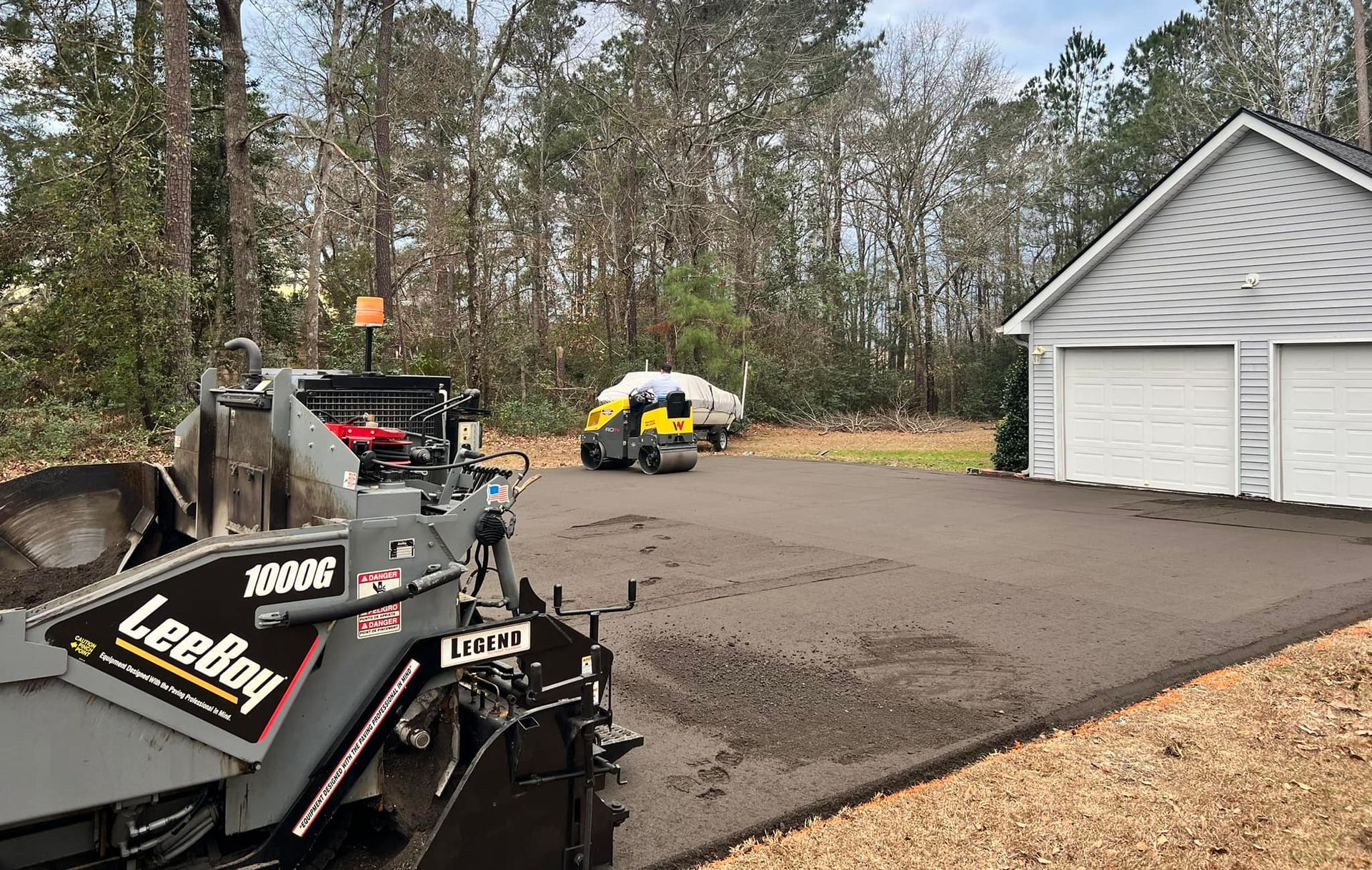 A machine is sitting in a driveway next to a garage.