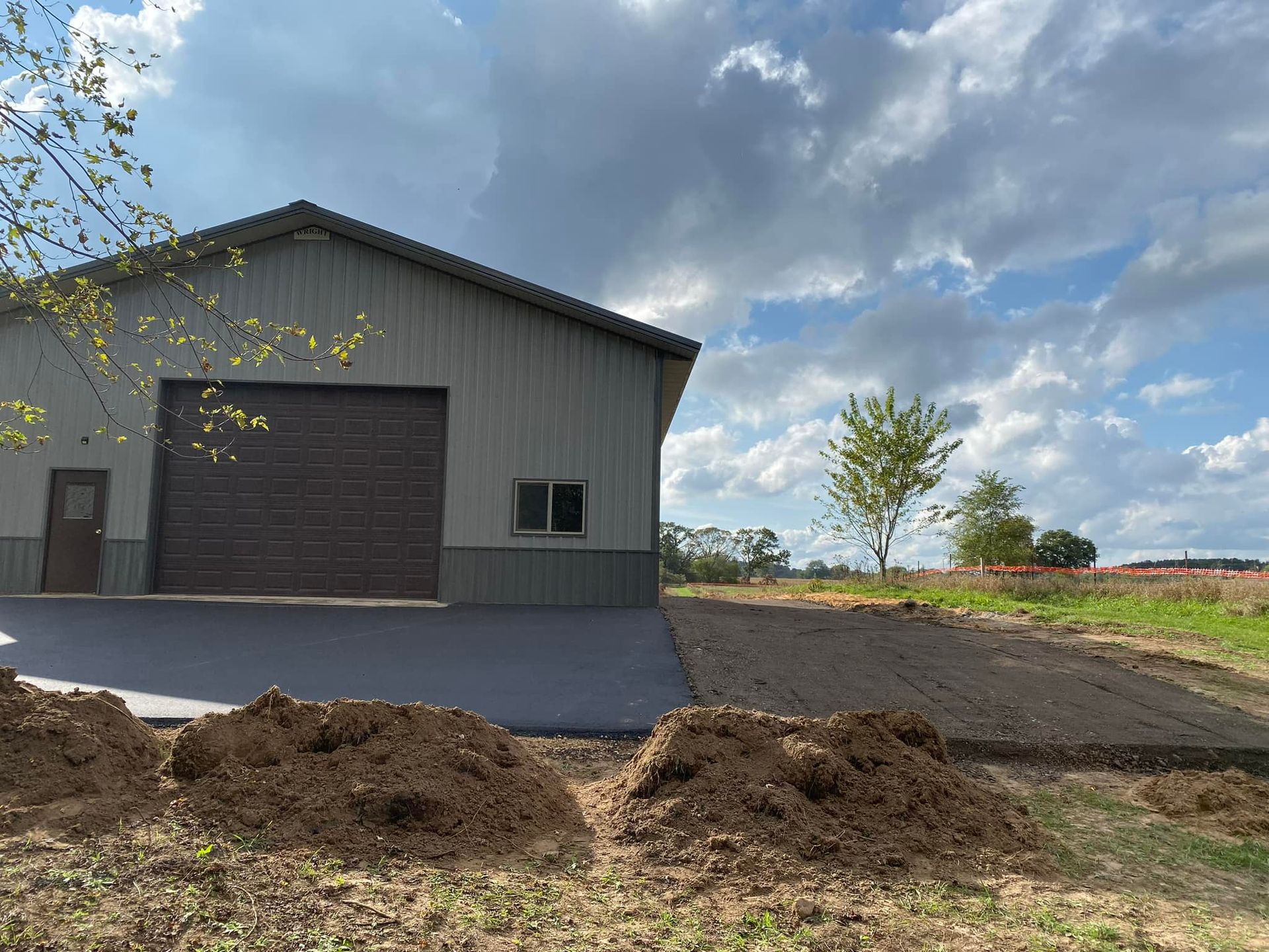 A garage with a large garage door is sitting in the middle of a field.