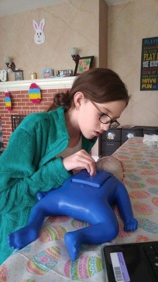 A young girl is sitting at a table playing with a blue toy.
