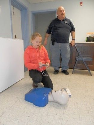 A little girl is kneeling down next to a mannequin.