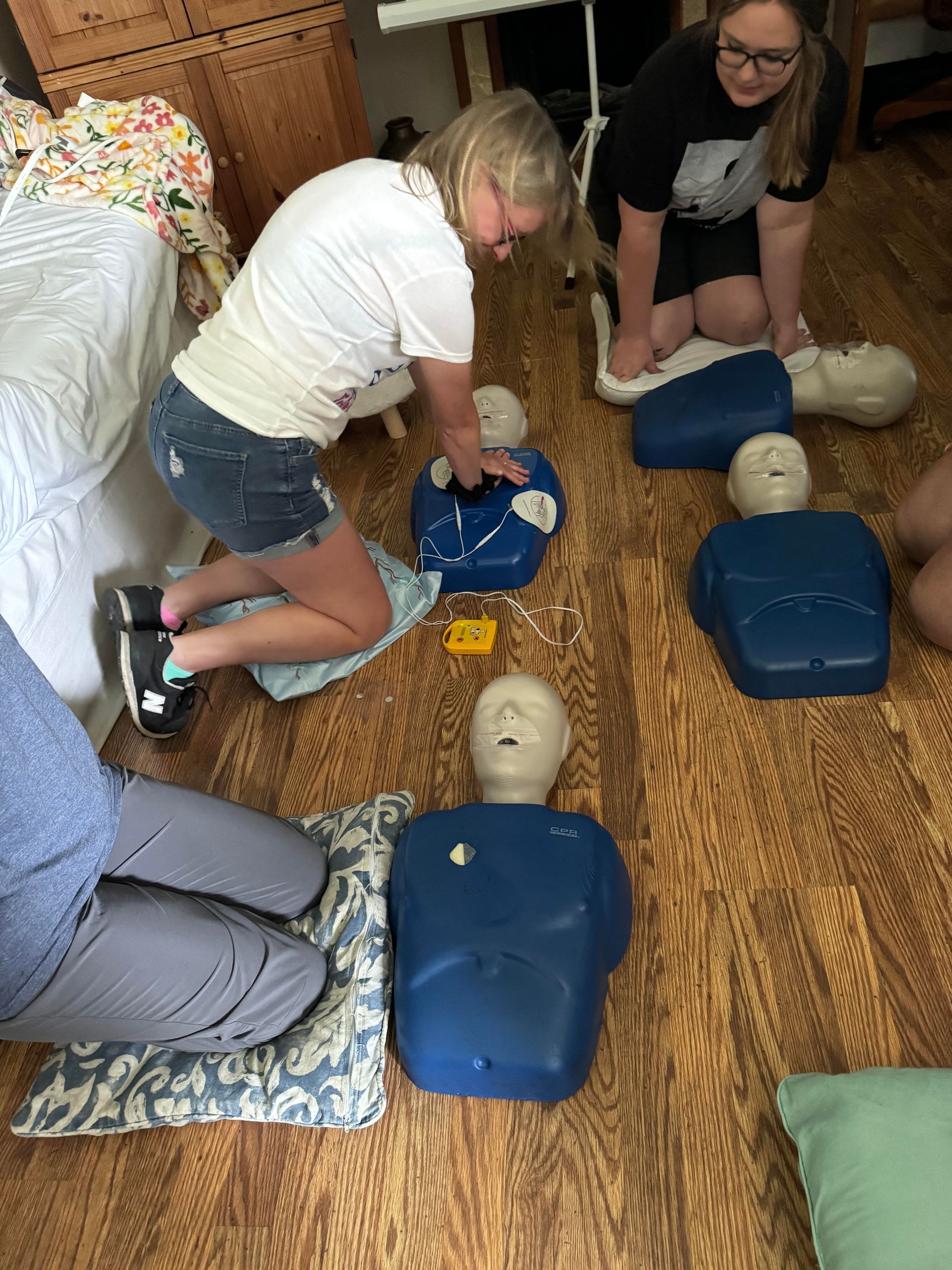A group of people are practicing first aid on mannequins.