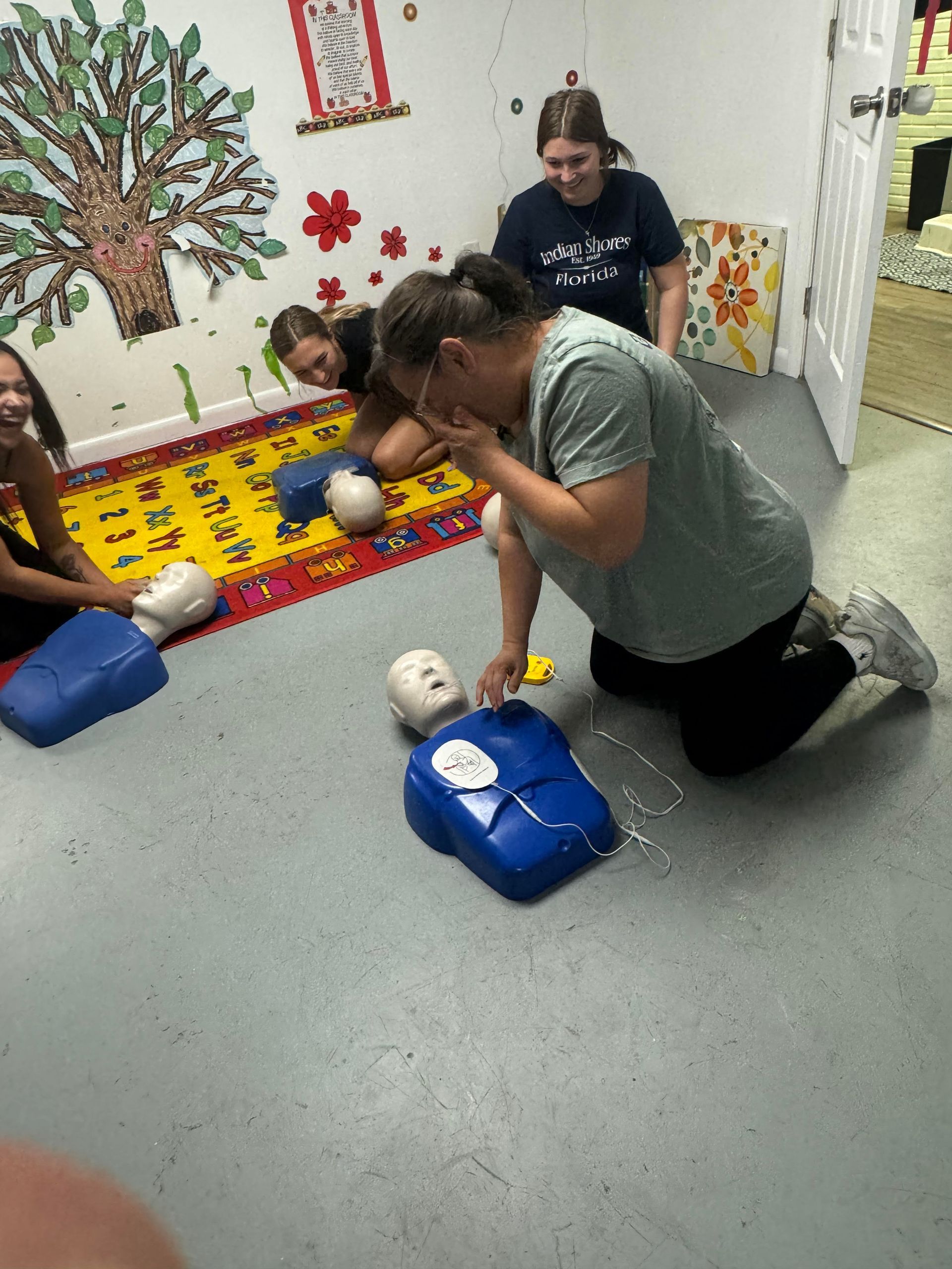 A group of people are kneeling down in a room with a mannequin.