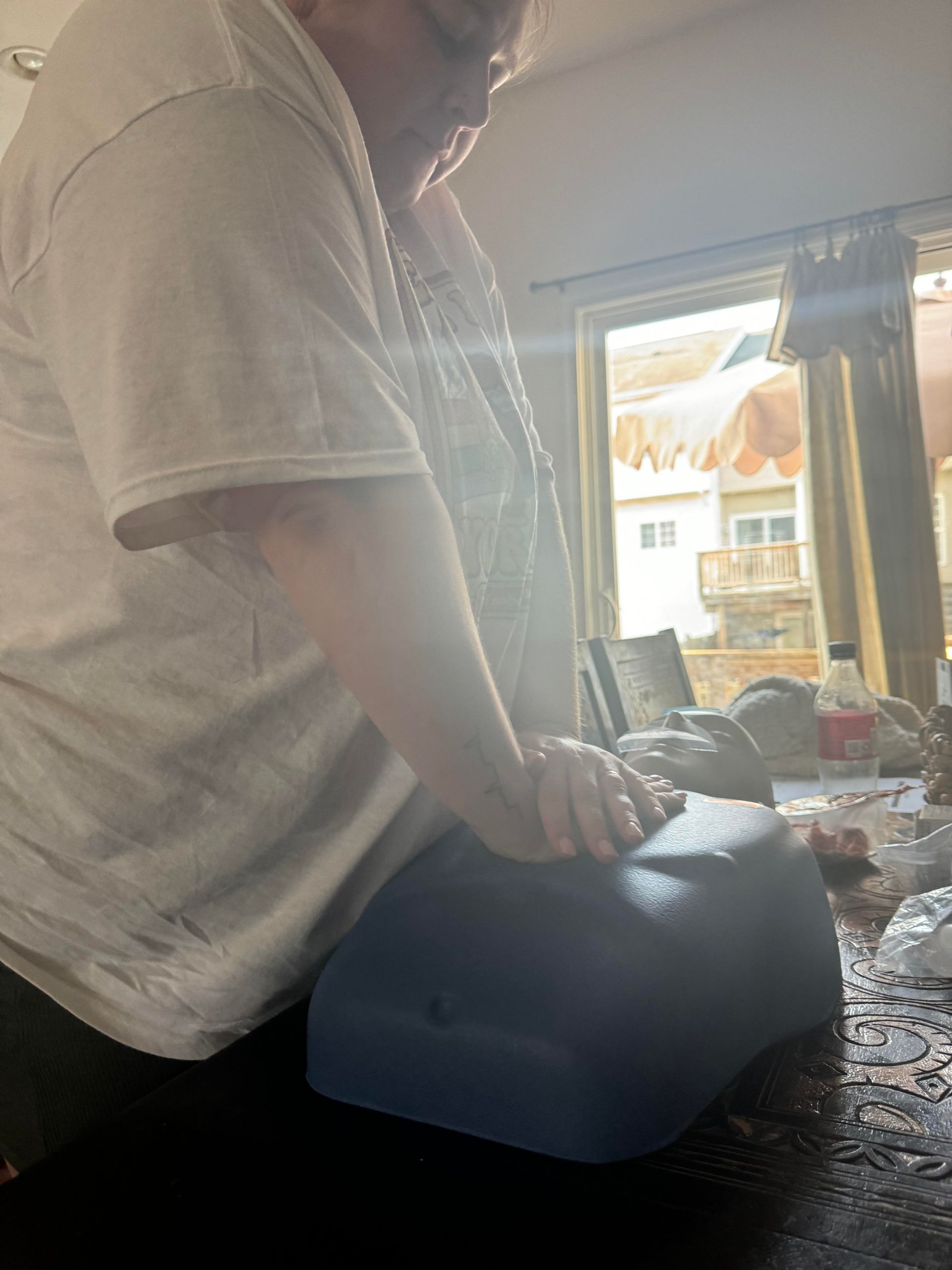A man is kneeling on a blue container on a table.