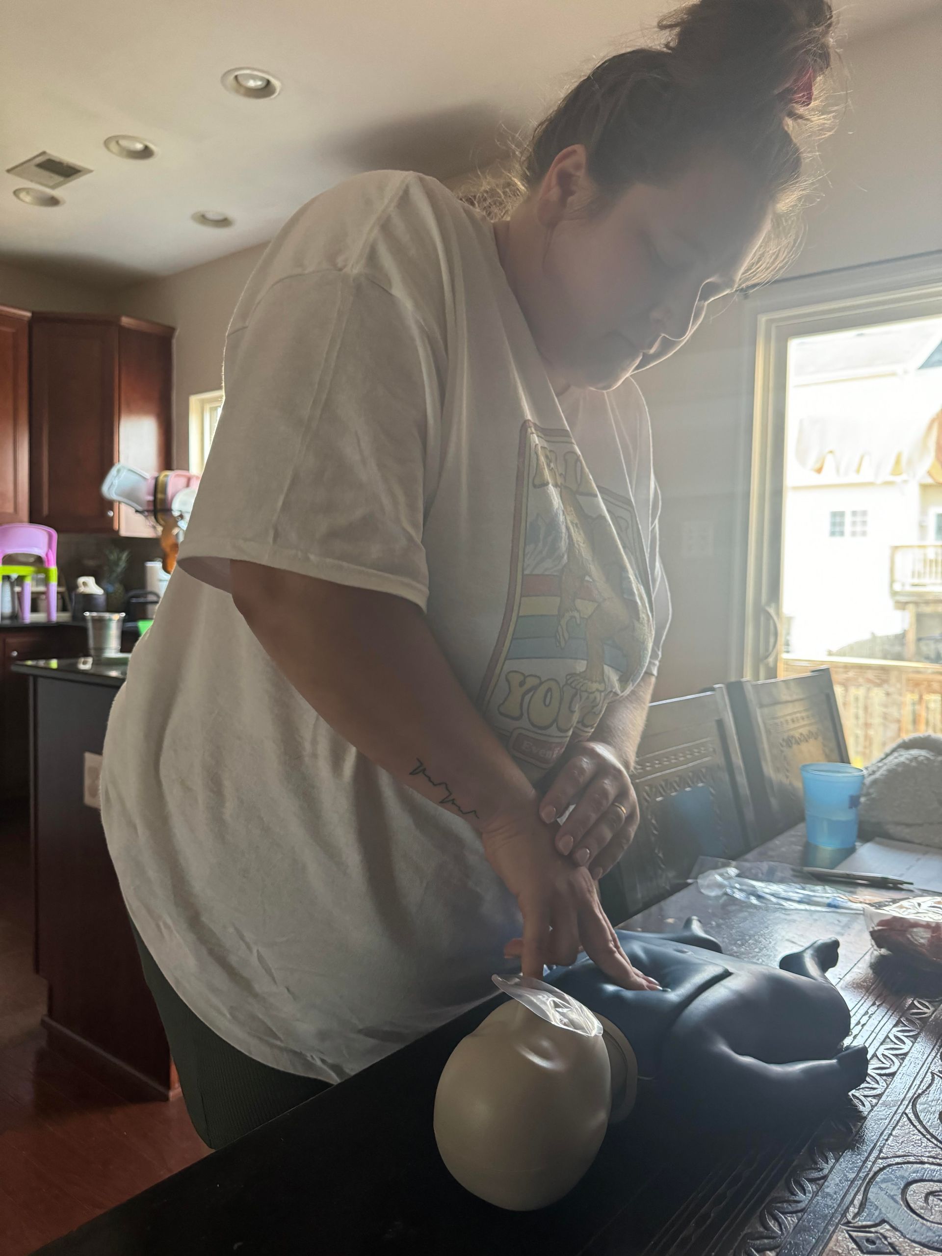 A woman in a white shirt is cutting a piece of dough on a table.