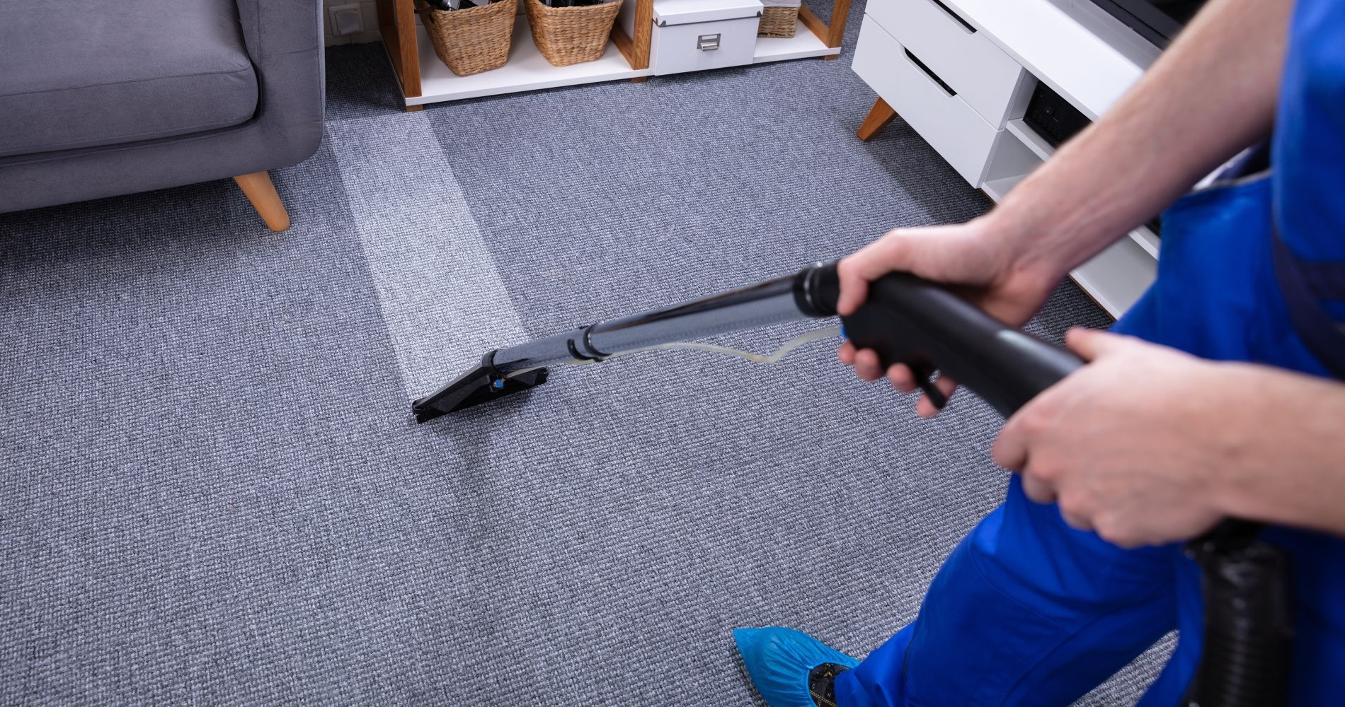 A person is cleaning a carpet with a vacuum cleaner in a living room.