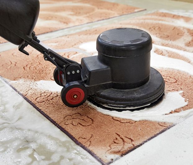 A person is cleaning a rug with a machine.