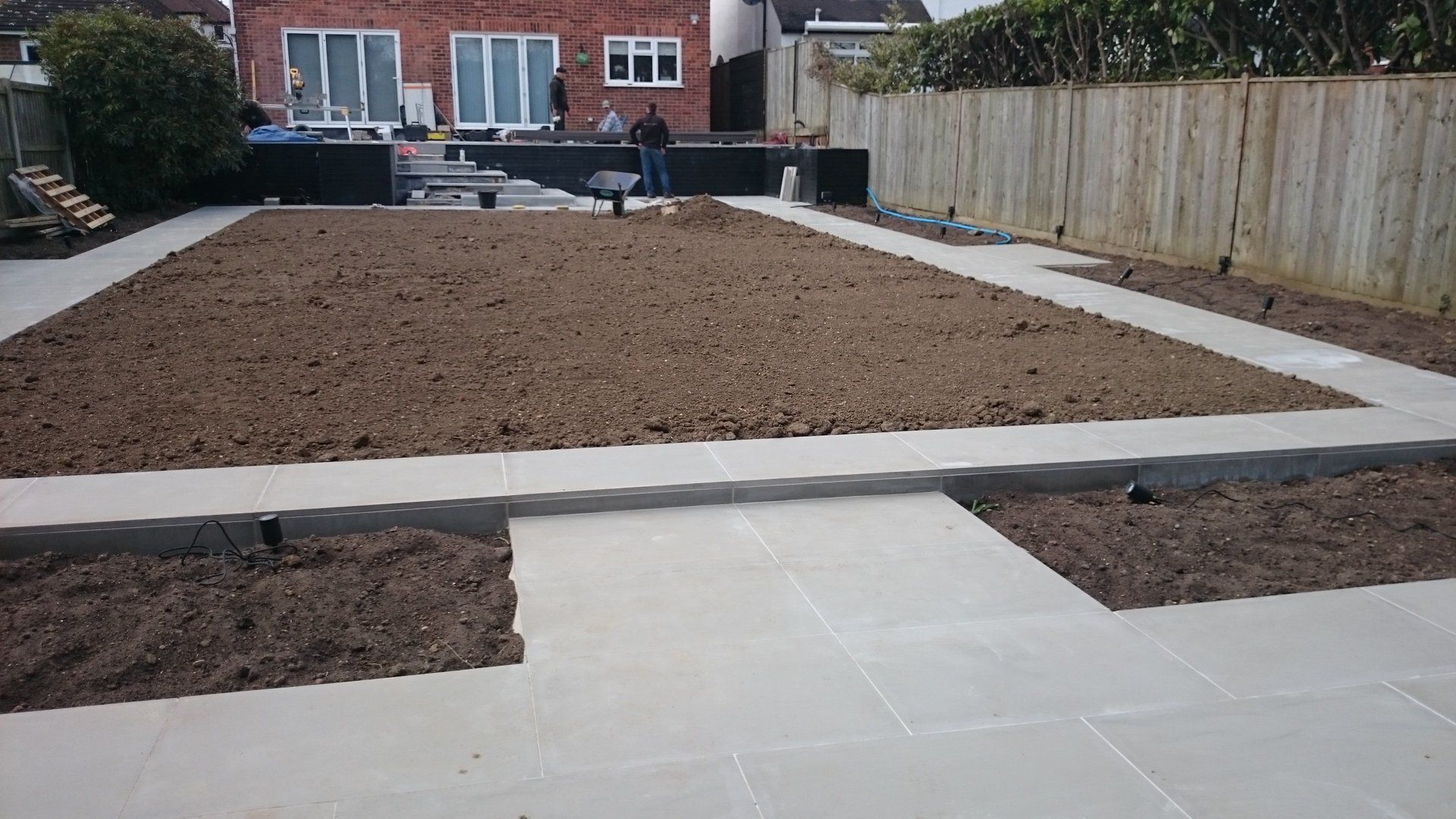 A man is standing in the middle of a dirt field in a backyard.