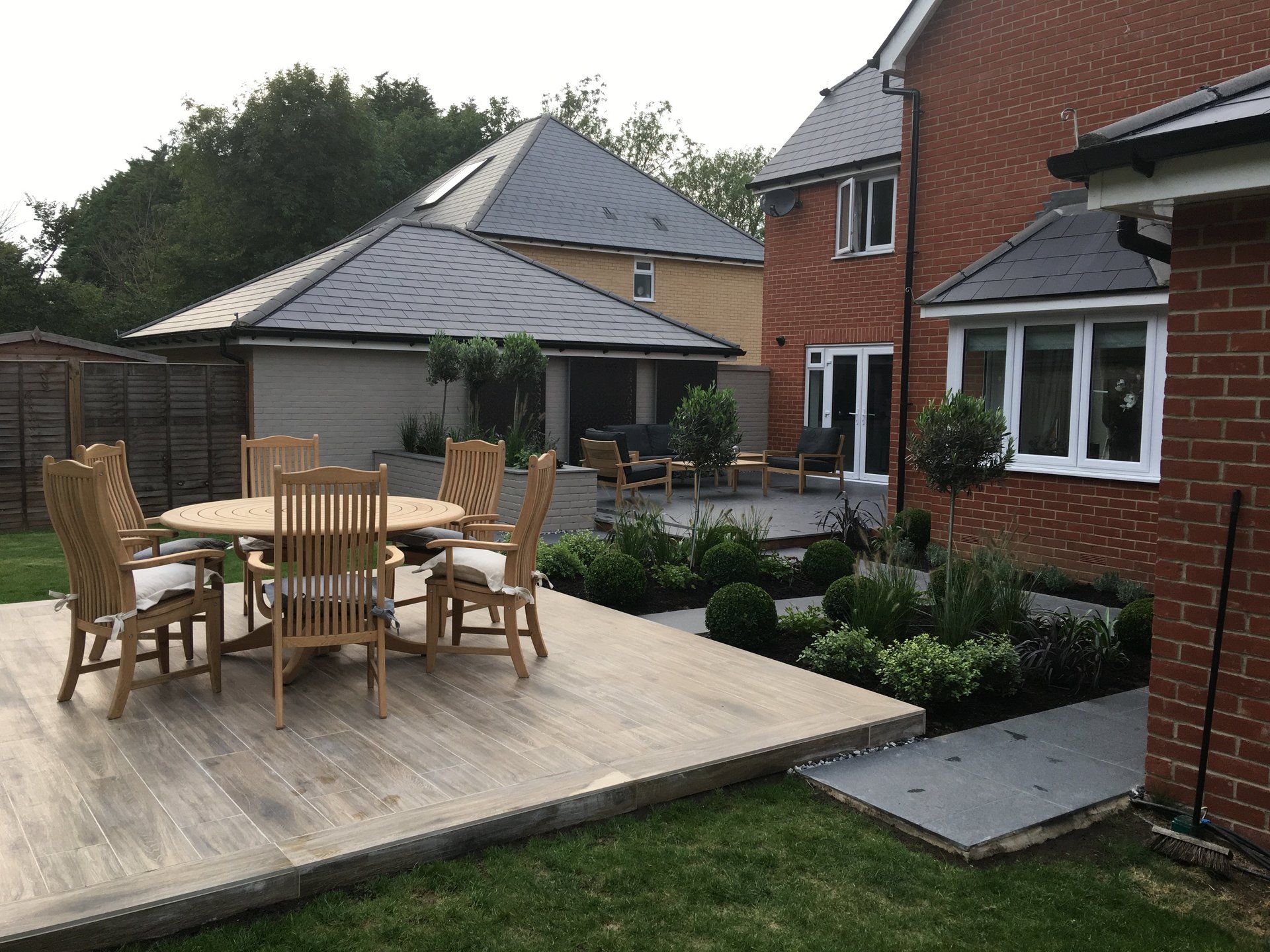 A patio with a table and chairs in front of a brick house.