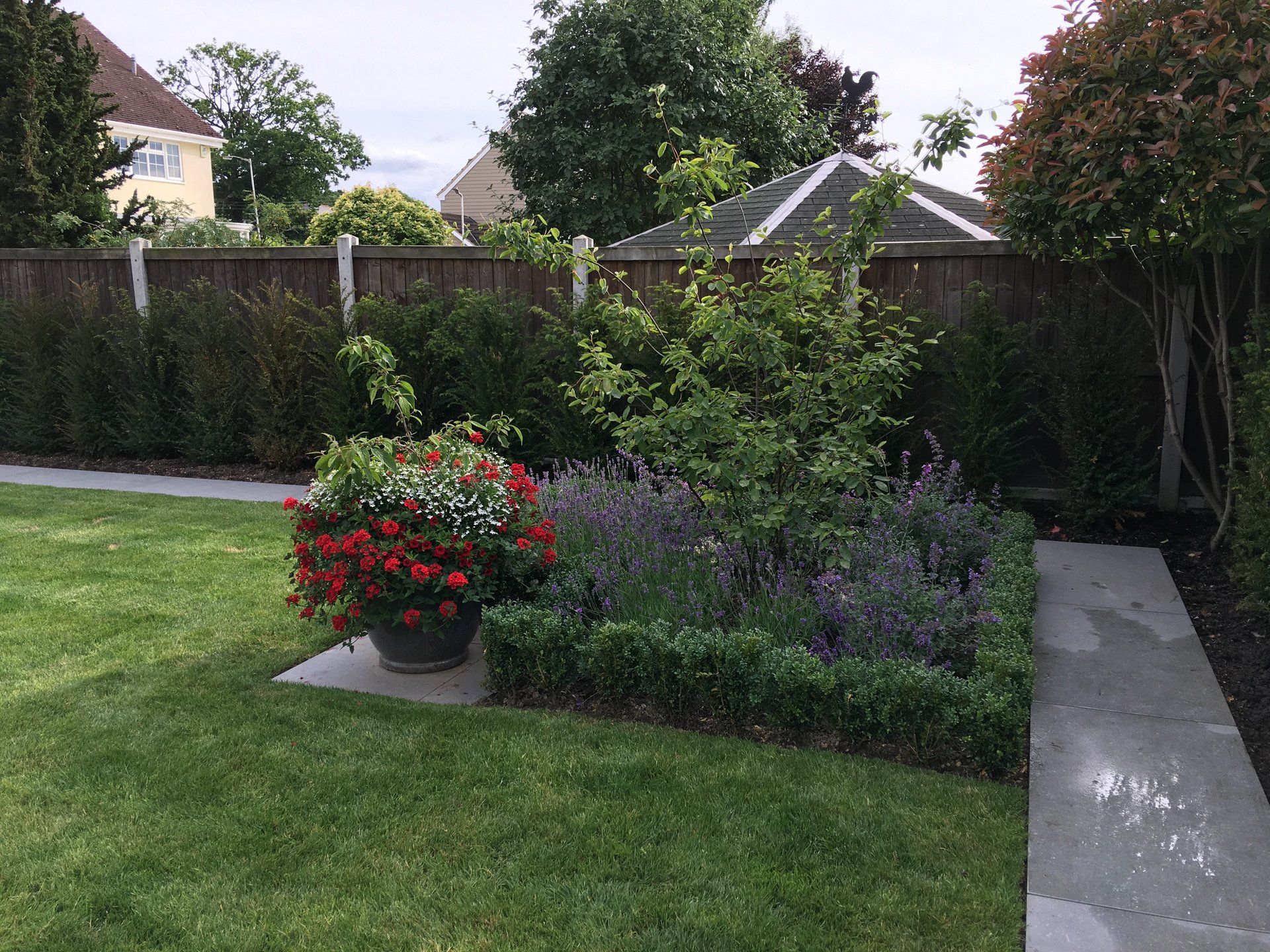 A garden with a fence and flowers in a pot