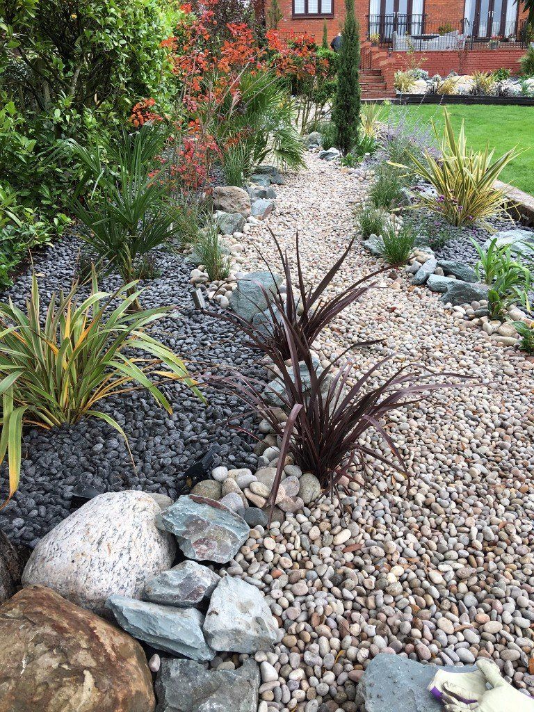 A garden filled with rocks , plants and flowers.