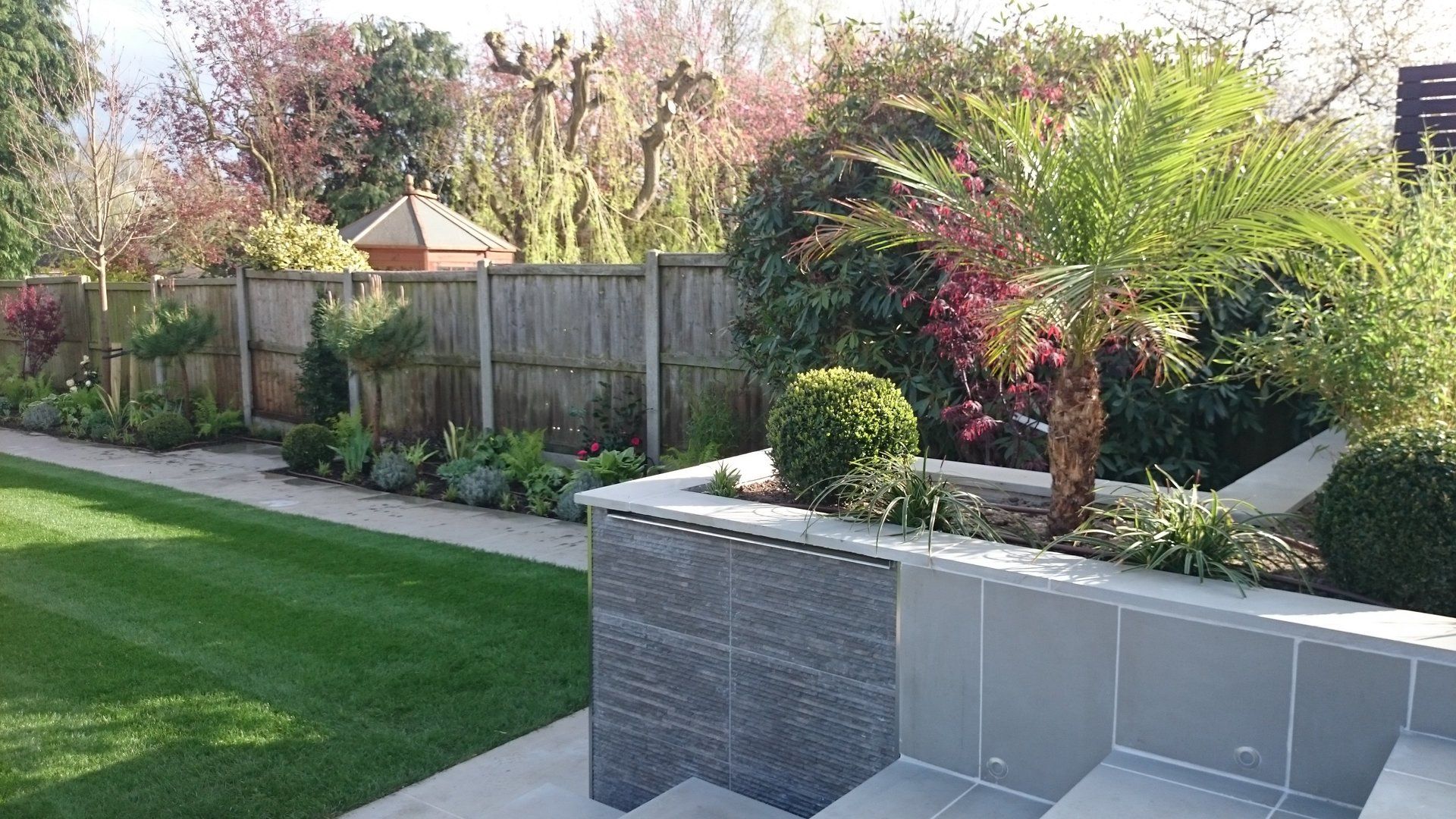 A lush green garden with a wooden fence and stairs leading up to it.