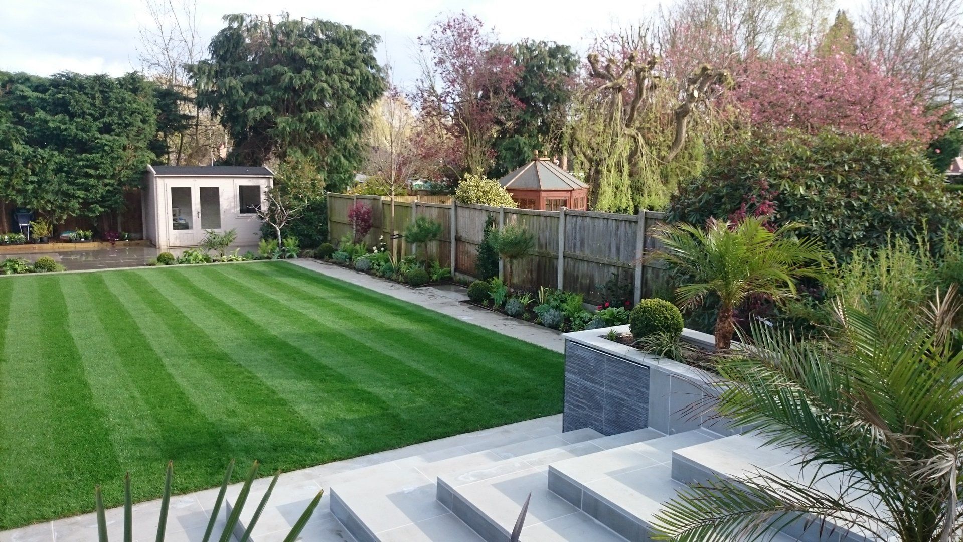 A lush green lawn with a shed in the background