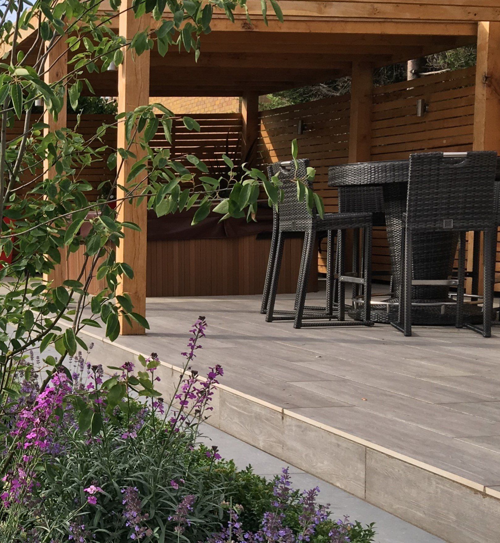 A patio with a table and chairs and purple flowers