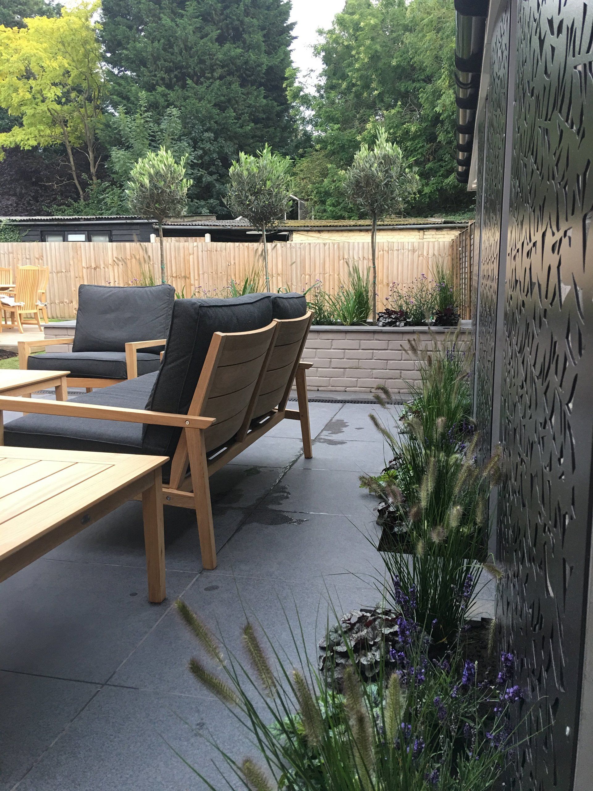 A patio with a couch and chairs and a waterfall in the background