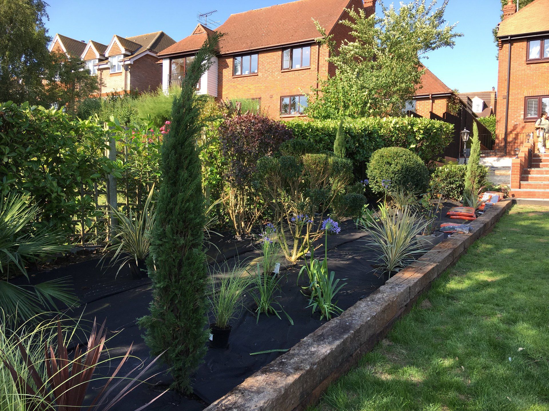 A lush green garden with a brick house in the background