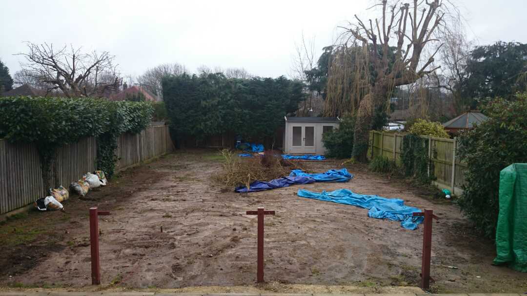 A muddy yard with a fence and a shed in the background.