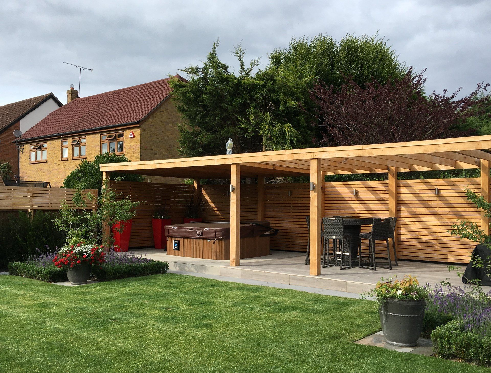 A backyard with a wooden pergola and a hot tub.