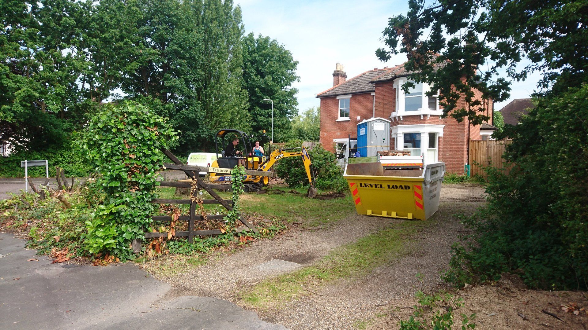 A yellow dumpster is parked in front of a house.