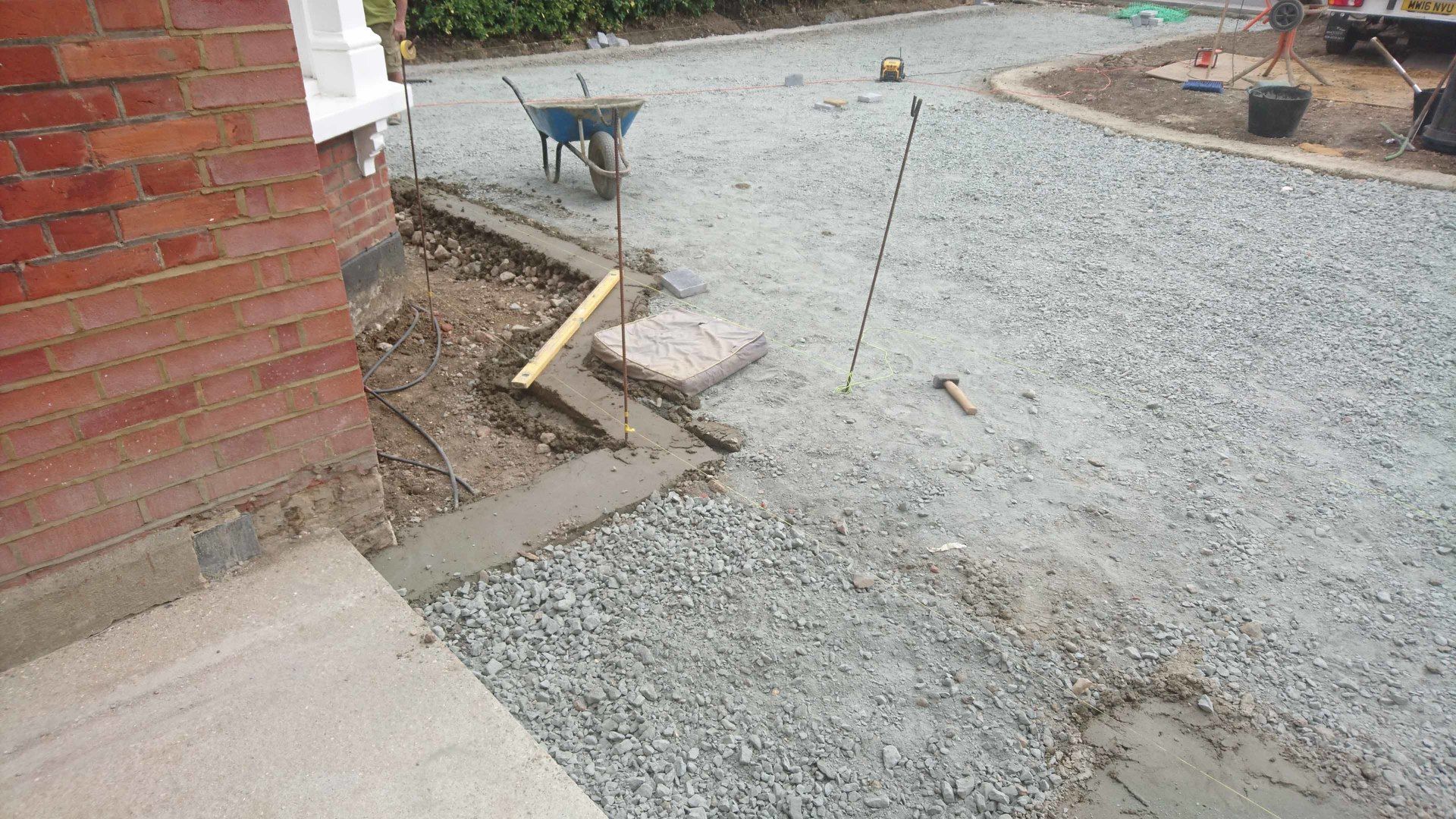A gravel driveway is being built in front of a brick building.