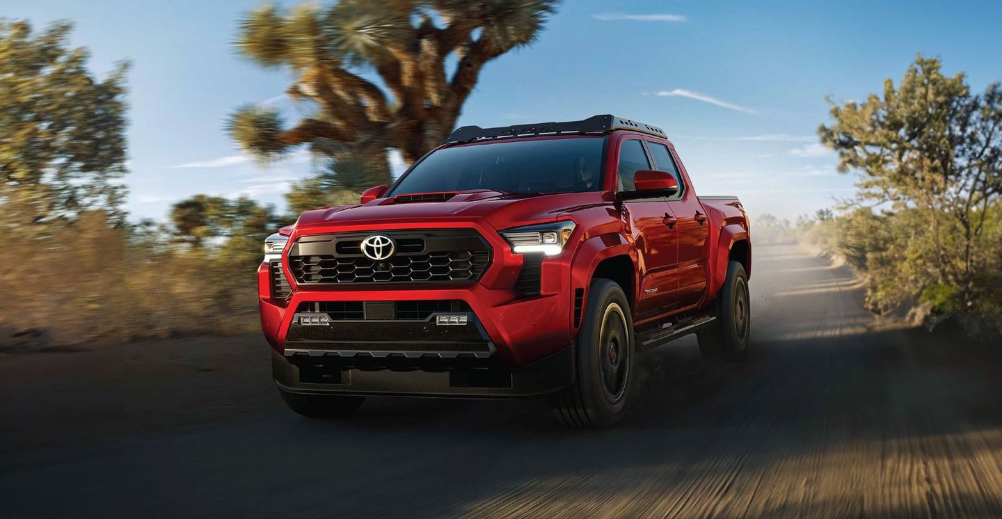 Un camión rojo circula por un camino de tierra.